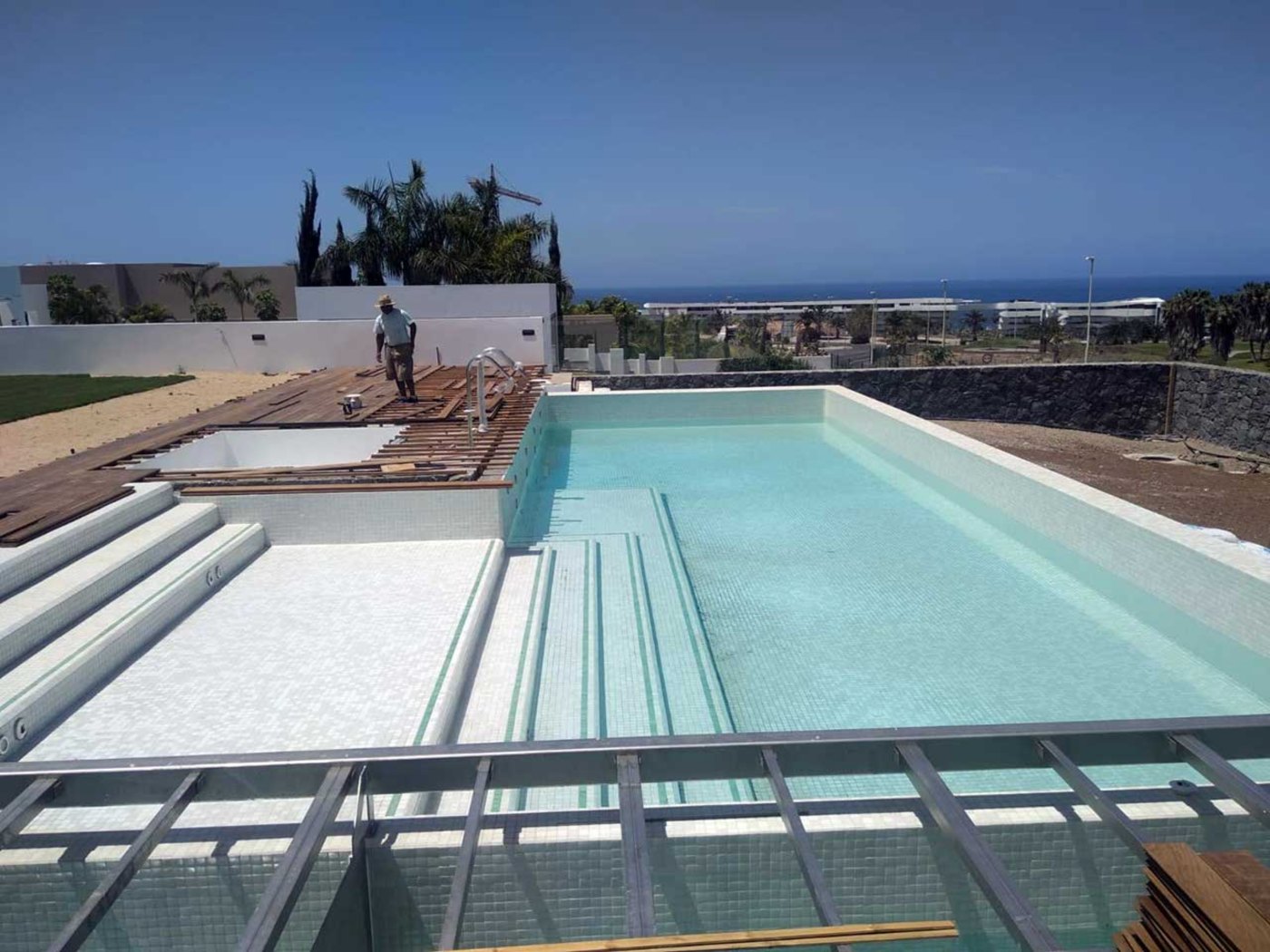 Piscina de gresite claro con escaleras de obra, con vistas al mar en el sur de Tenerife