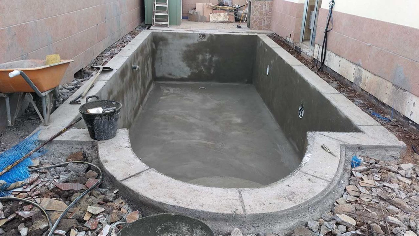Vaso de hormigón de una piscina terminado, con la coronación perimetral y el fondo todavía sin revestir